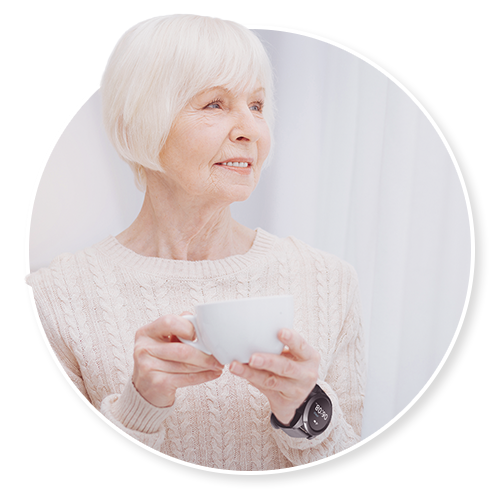 An older woman holding a teacup at home in soft natural light